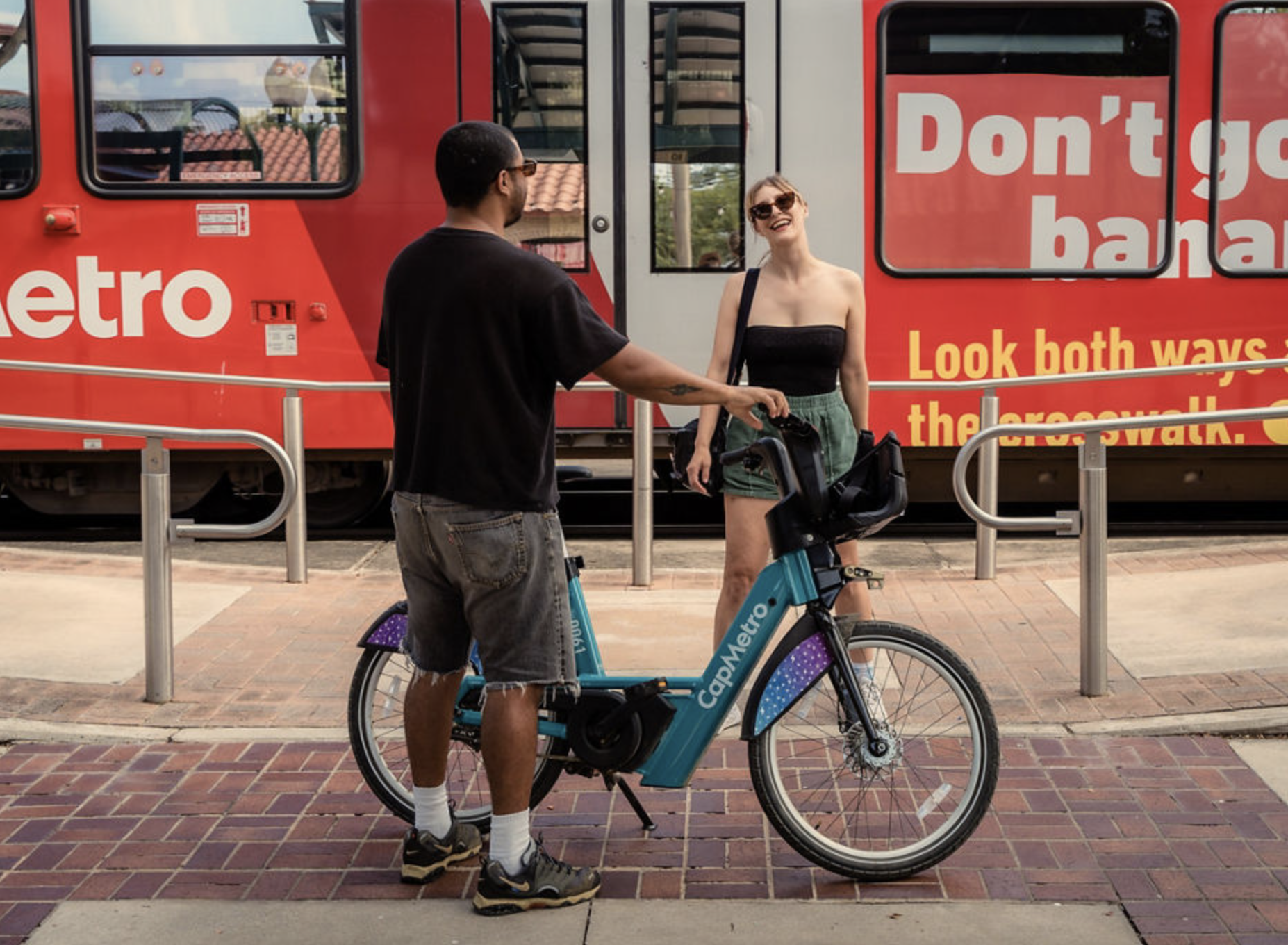 Festival goers riding CapMetro Bikeshare in front of CapMetro Rail
