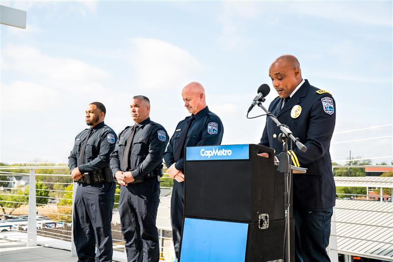 Photo of three new CapMetro Transit Police Department officers standing next to new Chief Bowie in front of a podium.