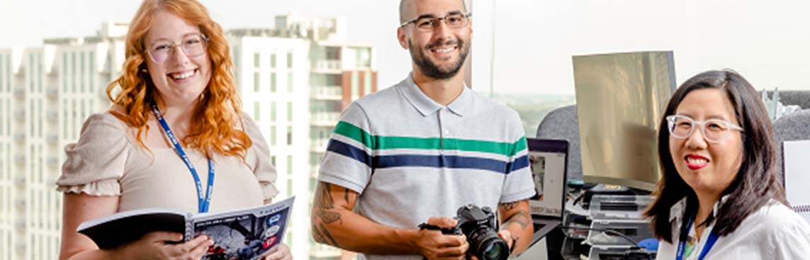 Three CapitalMetro administrative staff members standing in front of a desk smiling