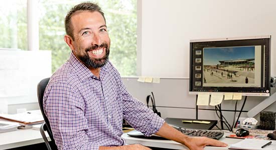 atp-corporate Young man in an office smiling in front of his work-station
