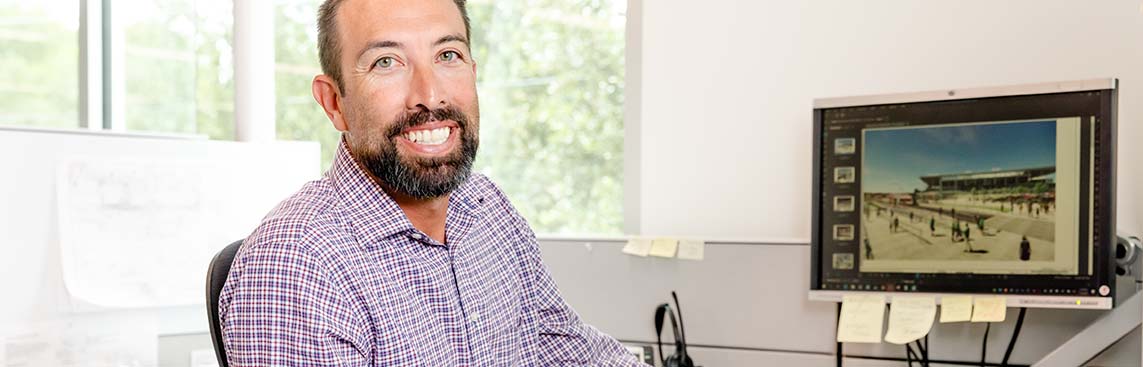 A happy Austin Transit Partnership Staff member sitting at his desk smiling