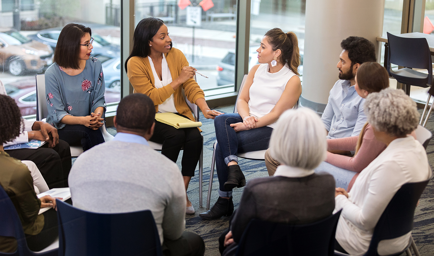 A very diverse group of people in an office setting, having a meeting