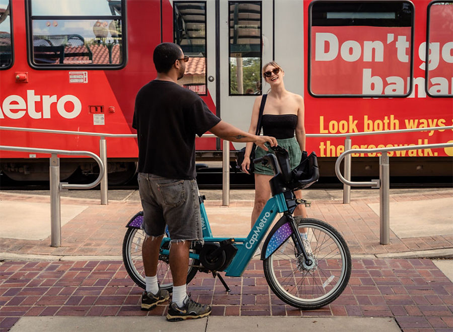 Festival goers riding CapMetro Bikeshare in front of CapMetro Rail